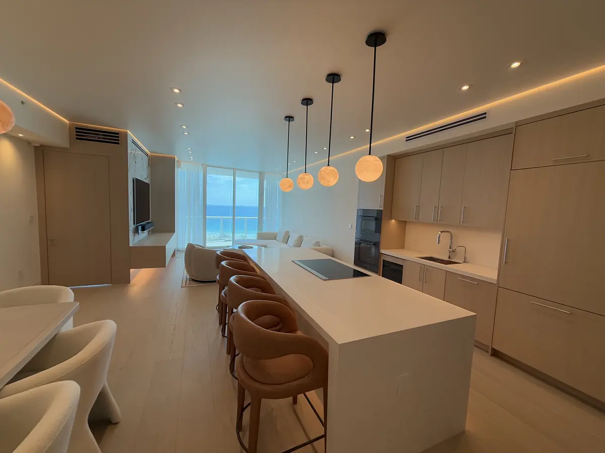 Completed kitchen renovation at Continuum South Tower, Miami Beach: waterfall island, alabaster pendants and wood cabinetry